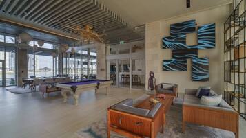A spacious living area with a pool table, comfortable seating, and a large abstract wall art piece.