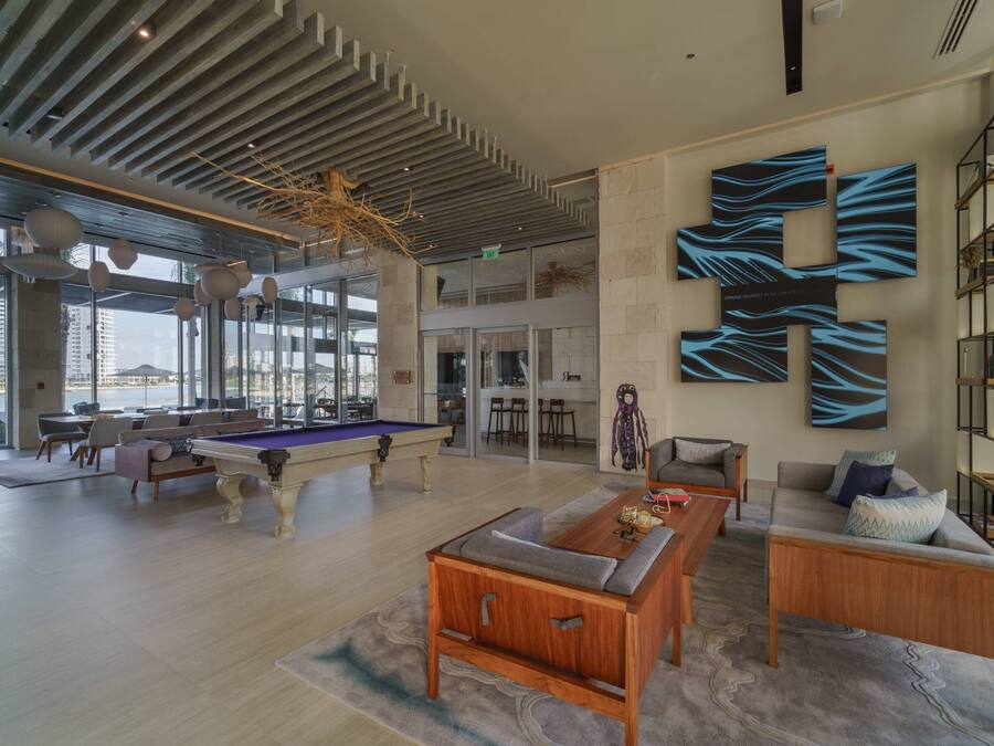 A spacious living area with a pool table, comfortable seating, and a large abstract wall art piece.