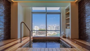 A modern spa area with a wooden floor, a hot tub, and a view of a cityscape through large windows. - Renaissance Cancun Resort & Marina (Cancún)