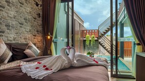 Ein Hotelzimmer mit einem Bett, Blick auf einen Swimmingpool und einer Treppe, die in einen Außenbereich führt.