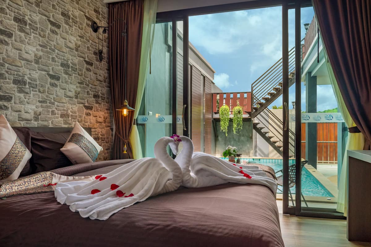 A hotel room with a bed, a view of a swimming pool, and a staircase leading to an outdoor area.
