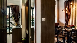 Ein modernes Esszimmer mit einem Holztisch, Stühlen und einer Chandelüstere. Im Hintergrund ist eine Treppe zu einem Außenbereich sichtbar.