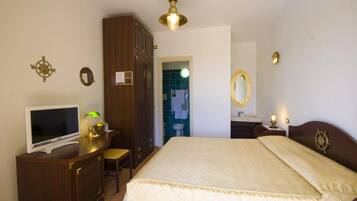 A bedroom with a bed, a desk, a television, and a wardrobe.