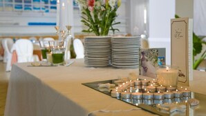 Et bord dækket op til en formel lejlighed med stearinlys, en blomsterdekoration og stablede tallerkener.