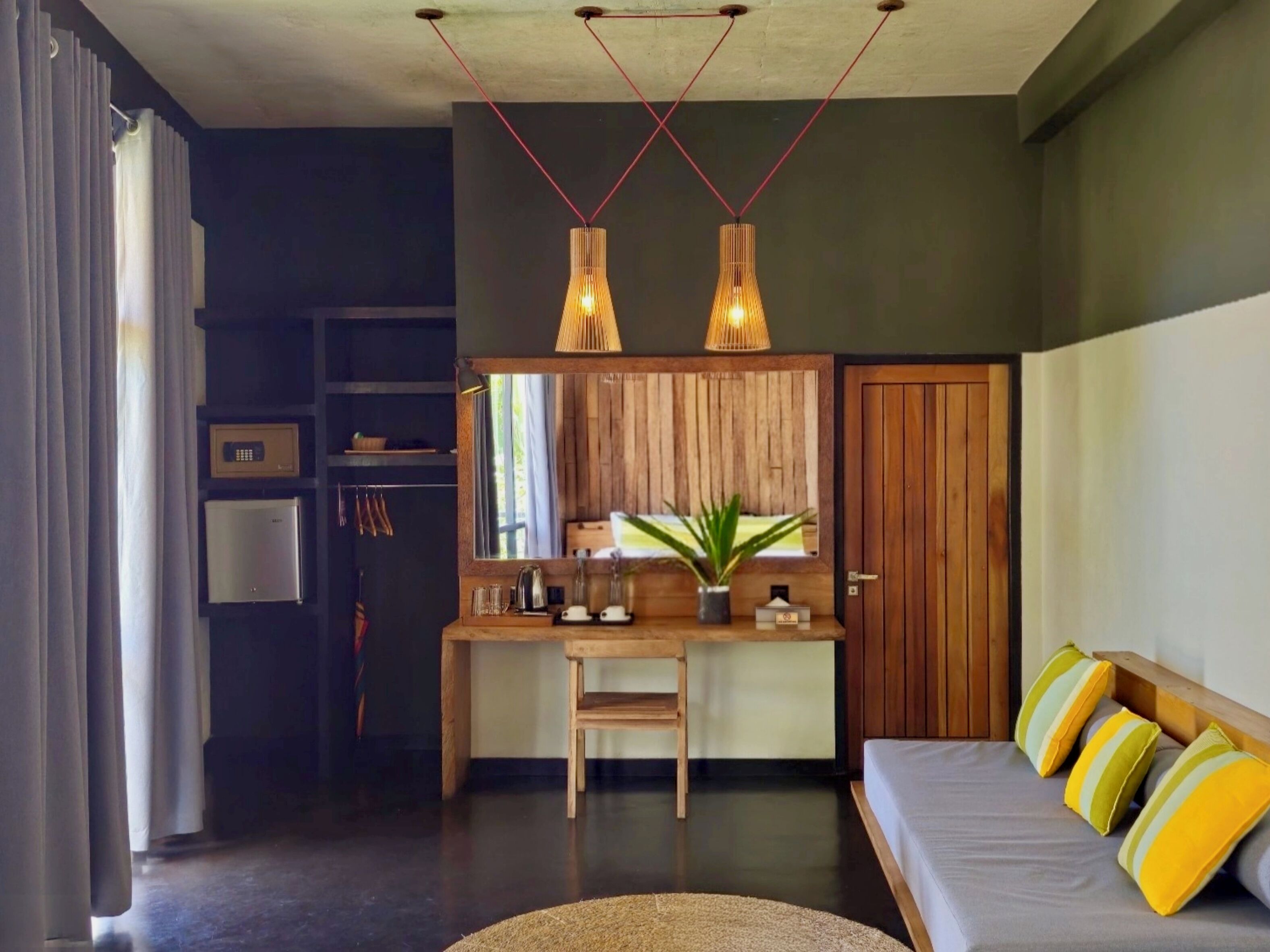 A modern living room with a sofa, a dining area with a wooden table, and a kitchen area with a refrigerator.