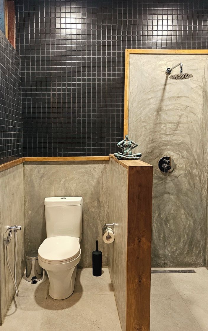 Un baño con inodoro, ducha y pared de mármol.