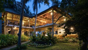 A multi-level modern house with a spacious outdoor area, surrounded by lush greenery and palm trees. - Lankavatara Ocean Retreat & Spa (Kalametiya)