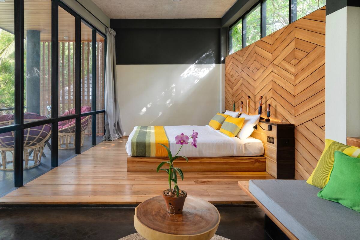 A modern bedroom with a large bed, a wooden headboard, and a view of the outdoors.
