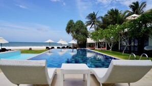 A poolside area with lounge chairs and umbrellas, a clear view of the ocean, and a tropical setting with palm trees. - Lankavatara Ocean Retreat & Spa (Kalametiya)