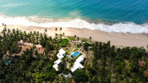 An aerial view of a beach resort with a swimming pool, palm trees, and a sandy beach. - Lankavatara Ocean Retreat & Spa (Kalametiya)