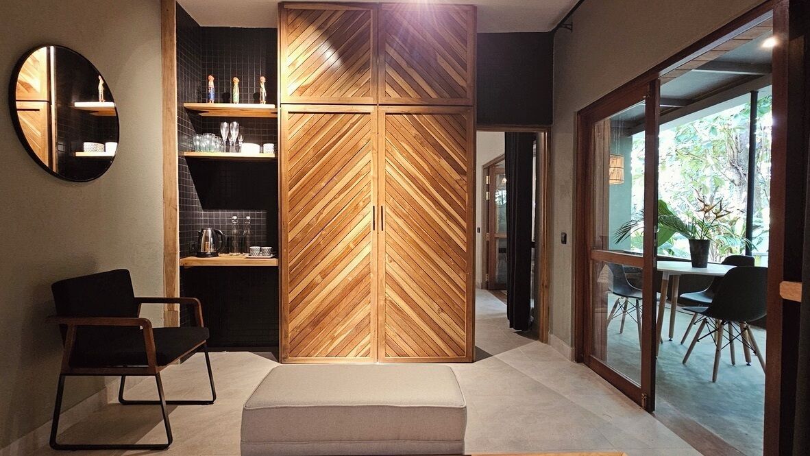 Una cocina moderna con pared de madera en patrón de espiga, un espejo redondo y una silla negra.