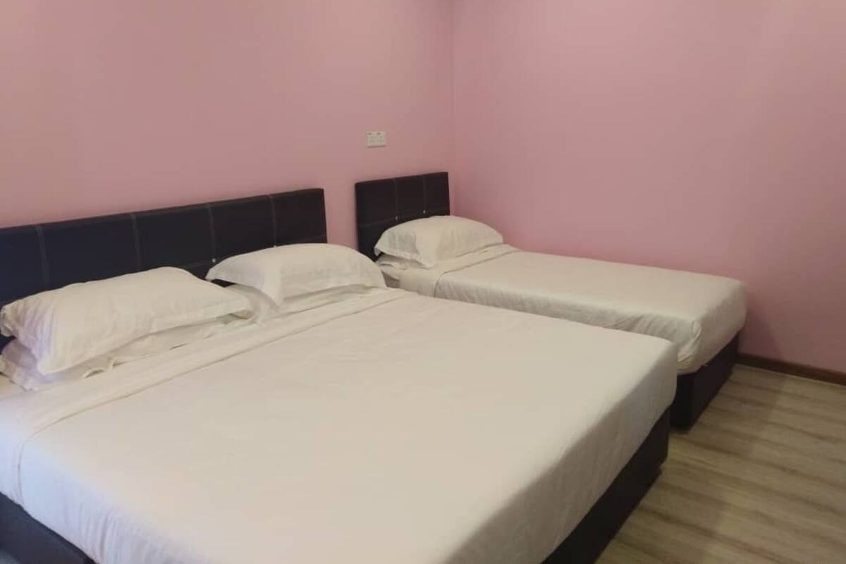 A room with two single beds, each with white bedding and headboards.