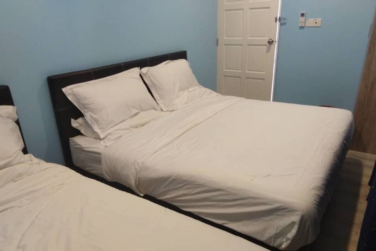 A room with two beds, each with white bedding and a dark headboard.