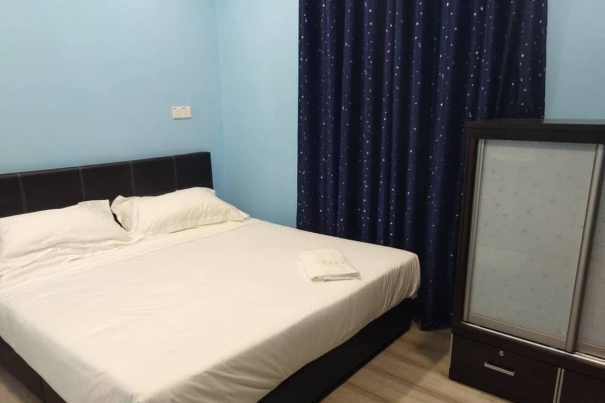 A bedroom with a bed, a television, and a curtain.