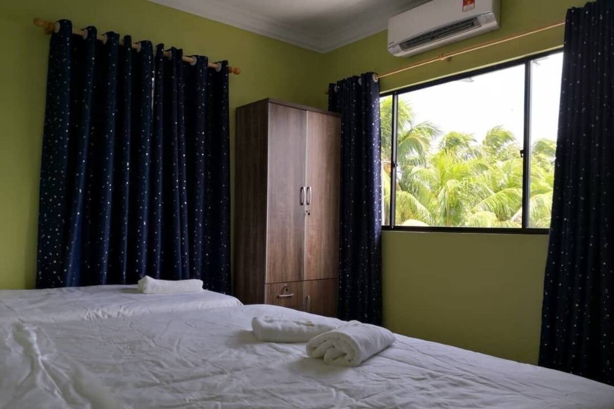 A hotel room with a bed, a wardrobe, and a window with curtains.