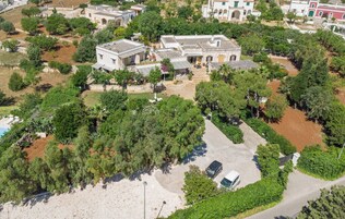 Vista aérea de una zona residencial con varias casas, un estacionamiento y abundante vegetación.
