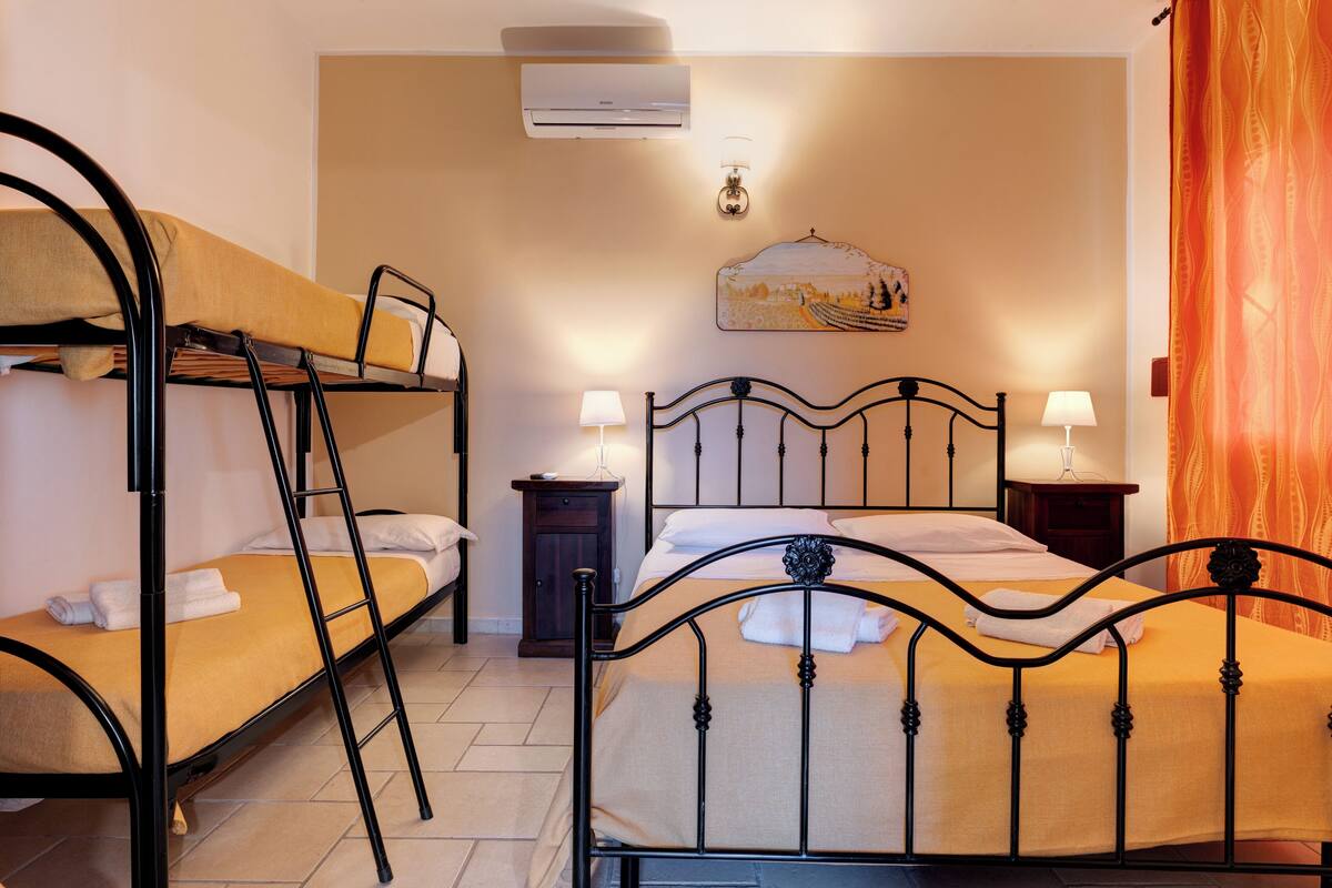 Une chambre avec un lit superposé, un lit simple, une table de chevet, une lampe et un appareil de climatisation.