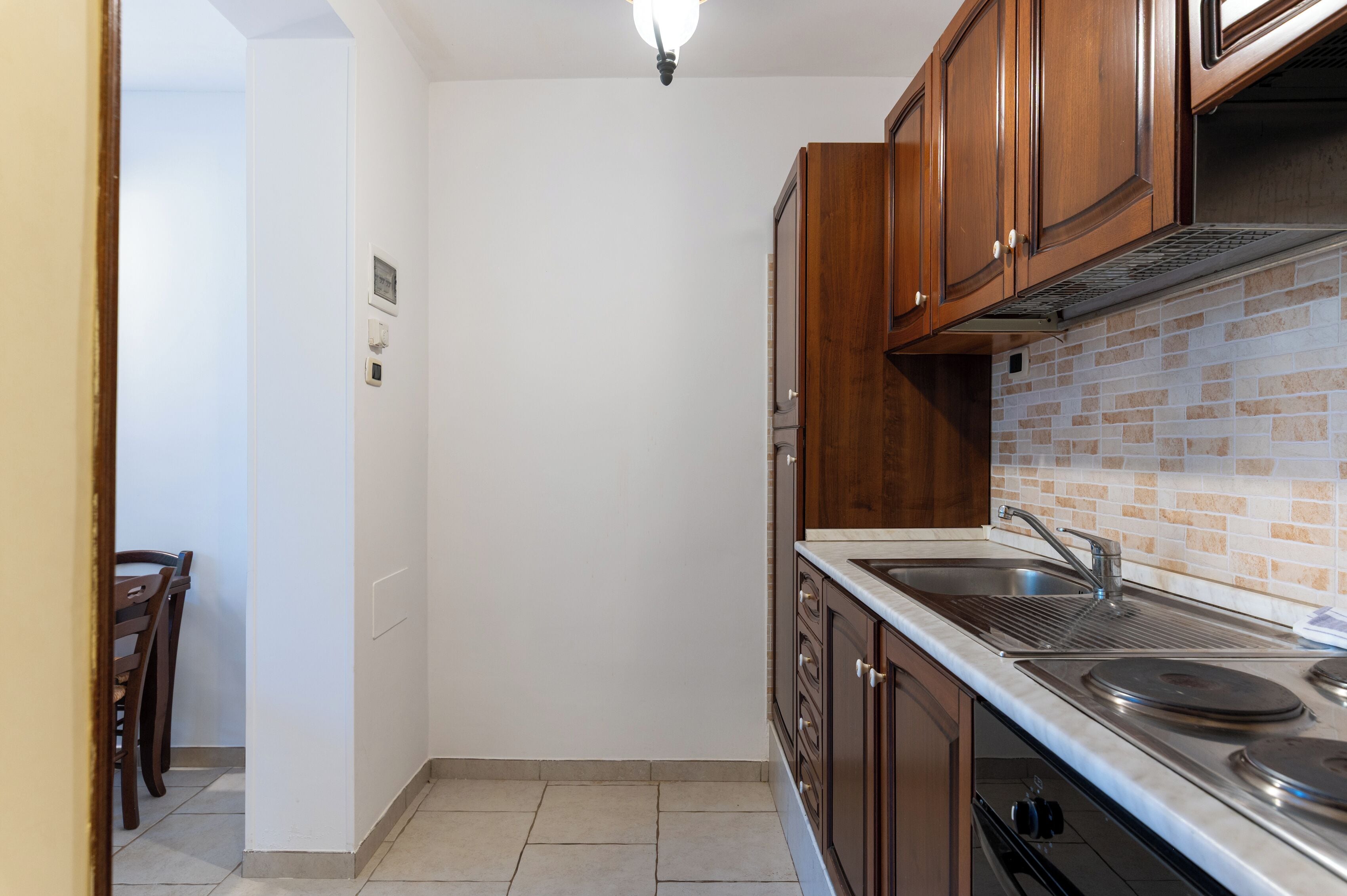 A kitchen with wooden cabinets, a stainless steel sink, and a tiled backsplash.