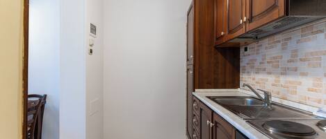 A kitchen with wooden cabinets, a stainless steel sink, and a tiled backsplash.