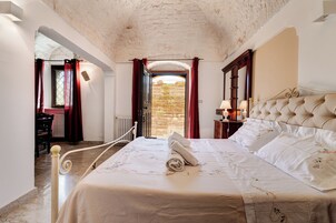 Un dormitorio con cama, mesita de noche, lámpara y vistas al exterior.