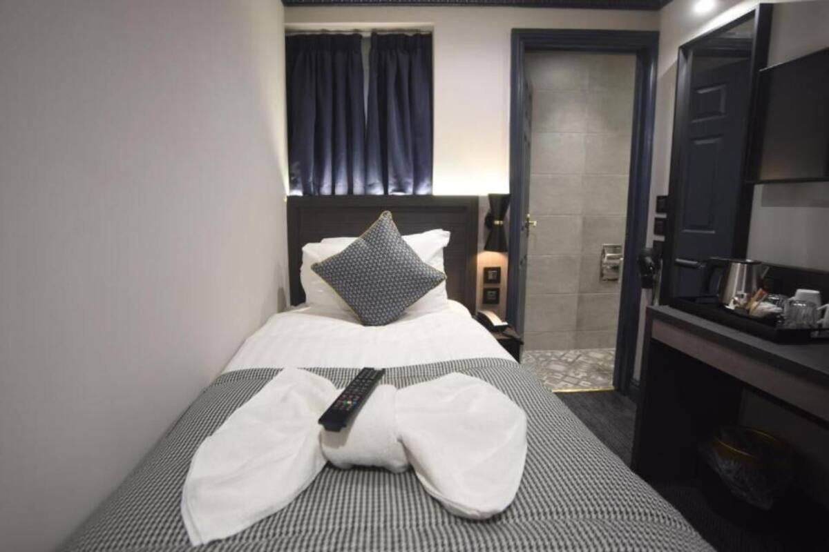 A hotel room with a bed, a TV, a desk, and a bathroom visible in the background.