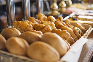 Diversos produtos de panificação, incluindo croissants e pão, expostos numa cesta.