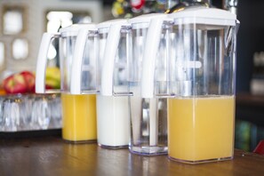 A row of clear glass containers with white lids, each containing a different colored liquid, placed on a wooden surface. - The Pack And Carriage London (London)
