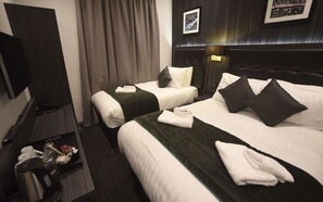 A hotel room with two beds, a TV, a desk with a kettle, and a framed picture on the wall. - The Pack And Carriage London (London)