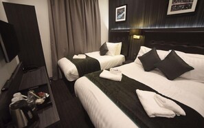 A hotel room with two beds, a bedside table with a kettle, and a TV mounted on the wall. - The Pack And Carriage London (London)