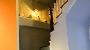 A staircase with wooden steps and a handrail, leading to a landing with a light fixture. - Le Petit Hanoi (Hanoi)