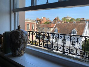 A view from a window with a decorative vase on the sill, overlooking a street with traditional buildings and a castle-like structure in the distance. - Guards View Windsor (Windsor)