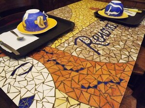 A mosaic table with a tray containing a blue and yellow cup and saucer, and a spoon. - Hôtel Renova (Nantes)