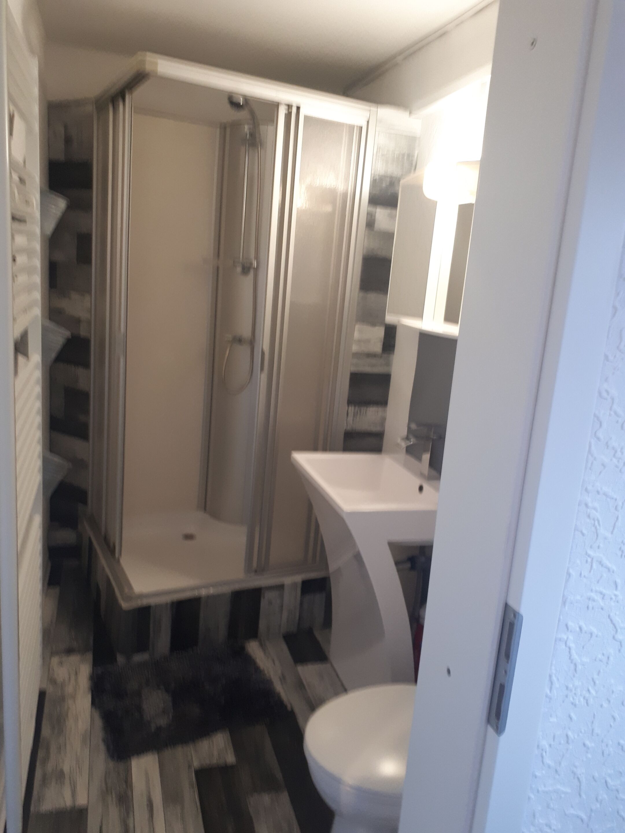 Un bagno piccolo ma funzionale, con doccia, WC e lavandino.