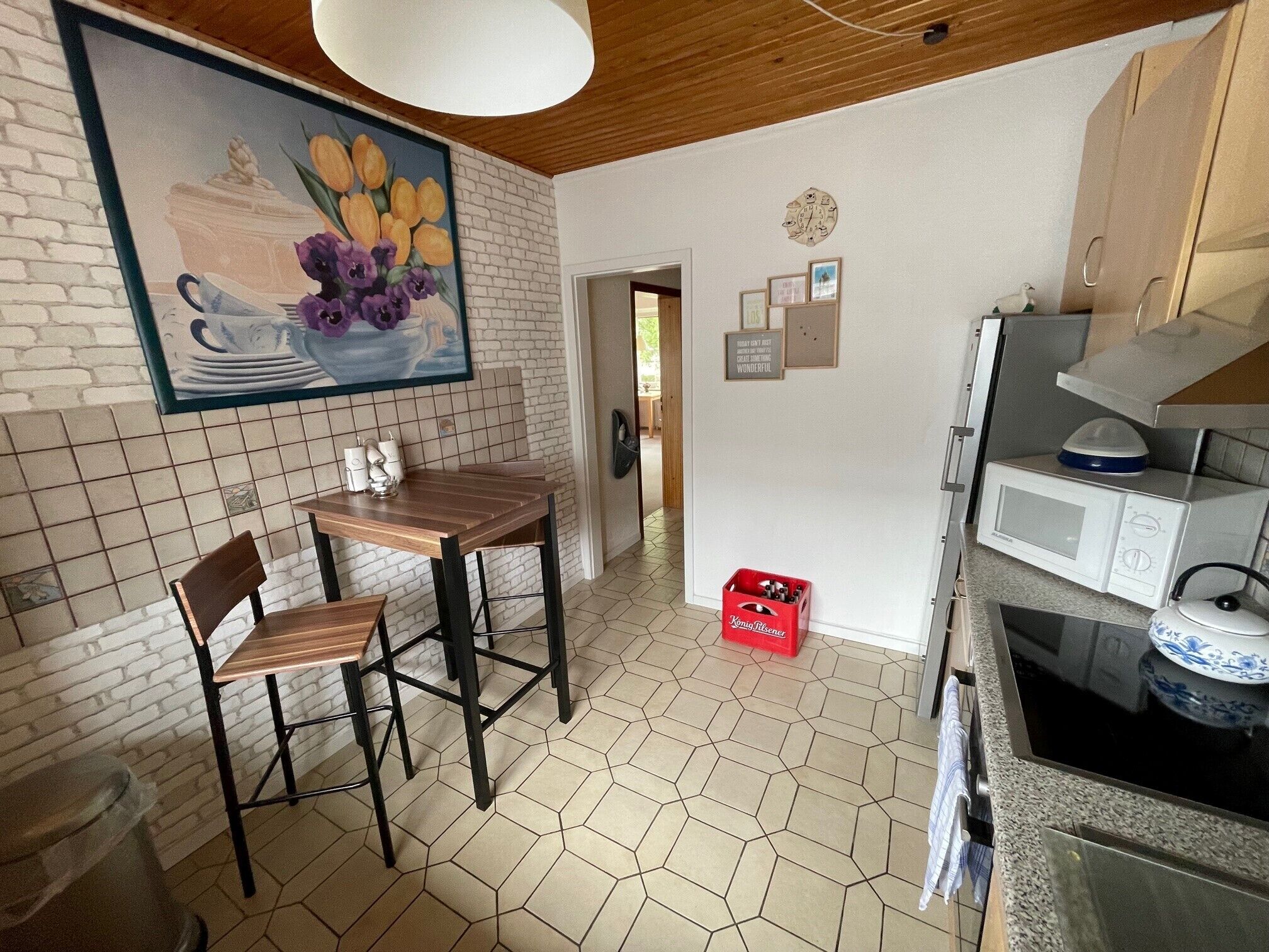Una cocina con una mesa y sillas de madera, un microondas y un caja roja.