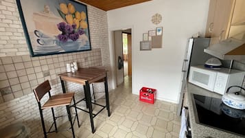 Una cocina con una mesa y sillas de madera, un microondas y un caja roja.