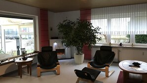 Ein stilvoller Lounge-Bereich mit Ledersesseln, einem runden Tisch, einer Zimmerpflanze und einem Kamin.