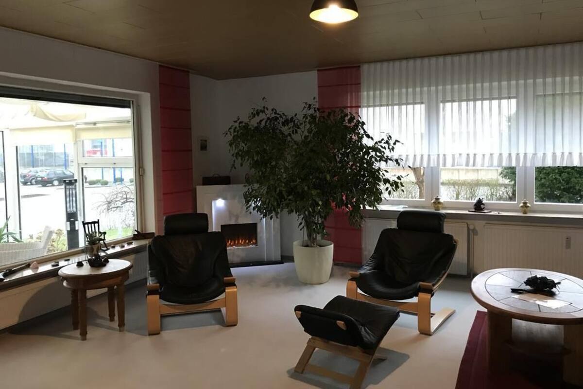 Ein stilvoller Lounge-Bereich mit Ledersesseln, einem runden Tisch, einer Zimmerpflanze und einem Kamin.