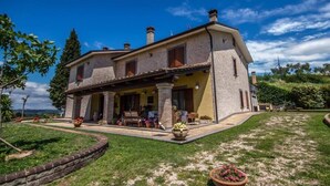 Une maison en pierre à deux étages, dotée d’un porche abrité, d’un mur en pierre qui entoure la propriété et d’une pelouse bien entretenue.