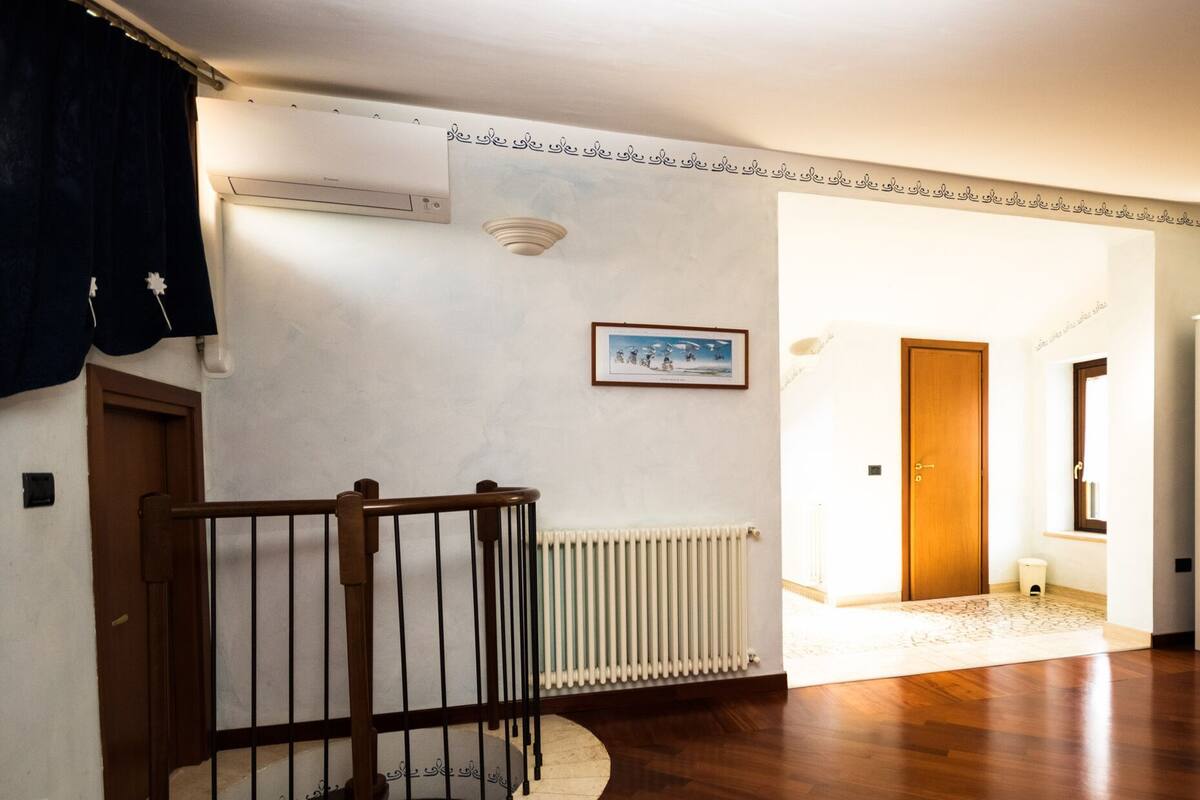A spacious hallway with a wooden staircase, a radiator, and a framed picture on the wall.