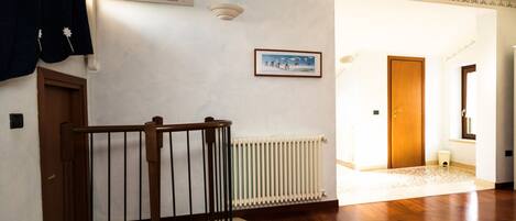 Ein geräumiger Flur mit einer Holztreppe, einem Heizkörper und einem gerahmten Bild an der Wand.
