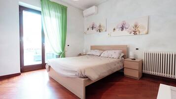 A bedroom with a wooden bed, a nightstand, a radiator, and a window with green curtains.