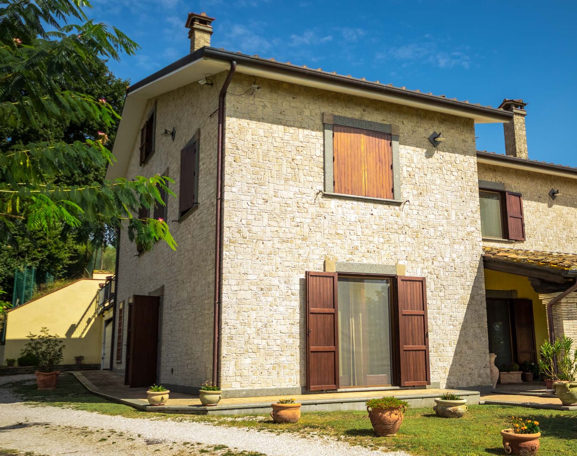 Una casa in pietra a due piani con un giardino.