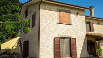 Una casa in pietra a due piani con un giardino.
