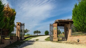 Une entrée fermée par un portail, avec un chemin de gravier qui la traverse.