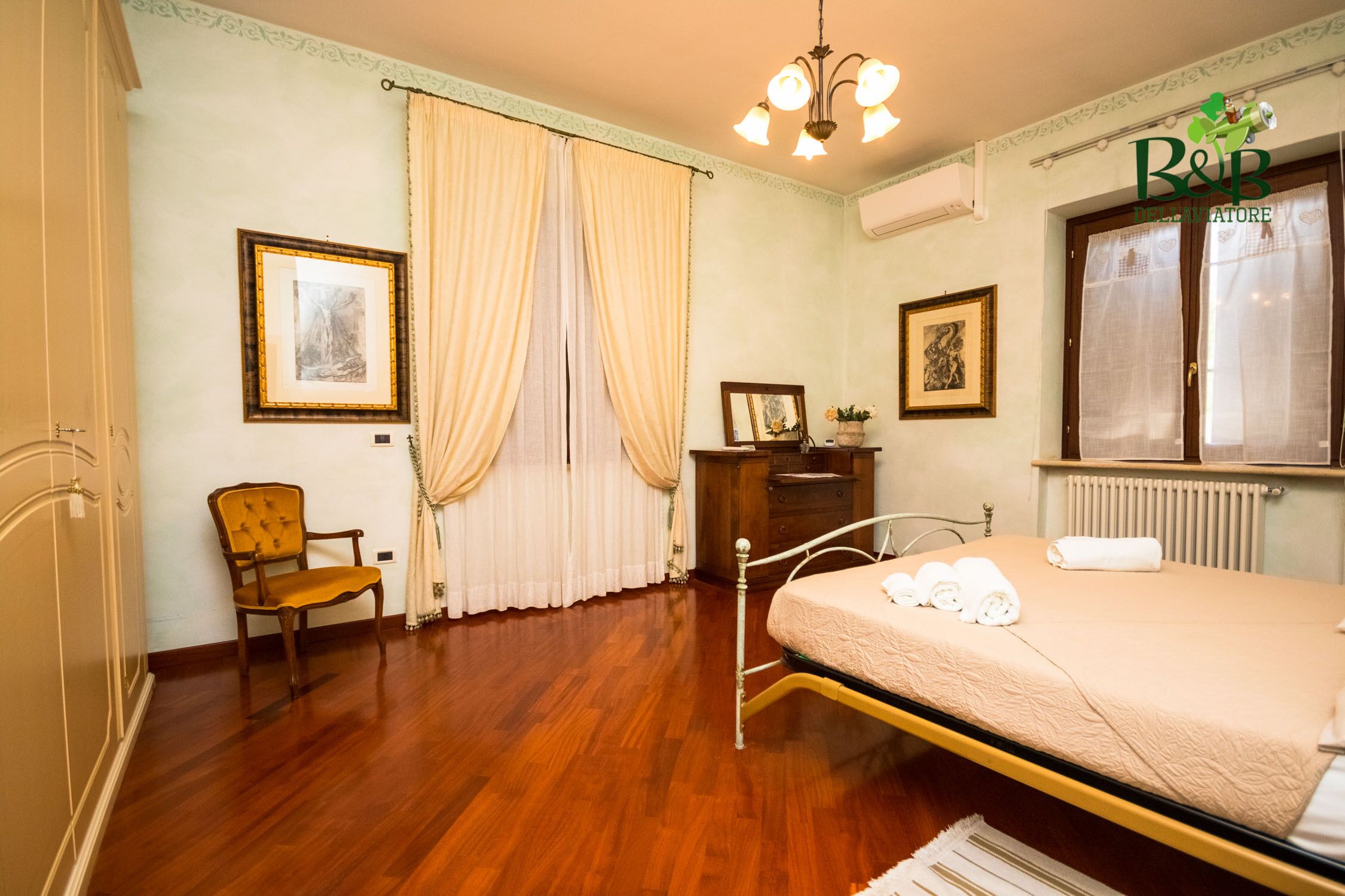 Een slaapkamer met een bed, een stoel, een kaptafel en gordijnen.