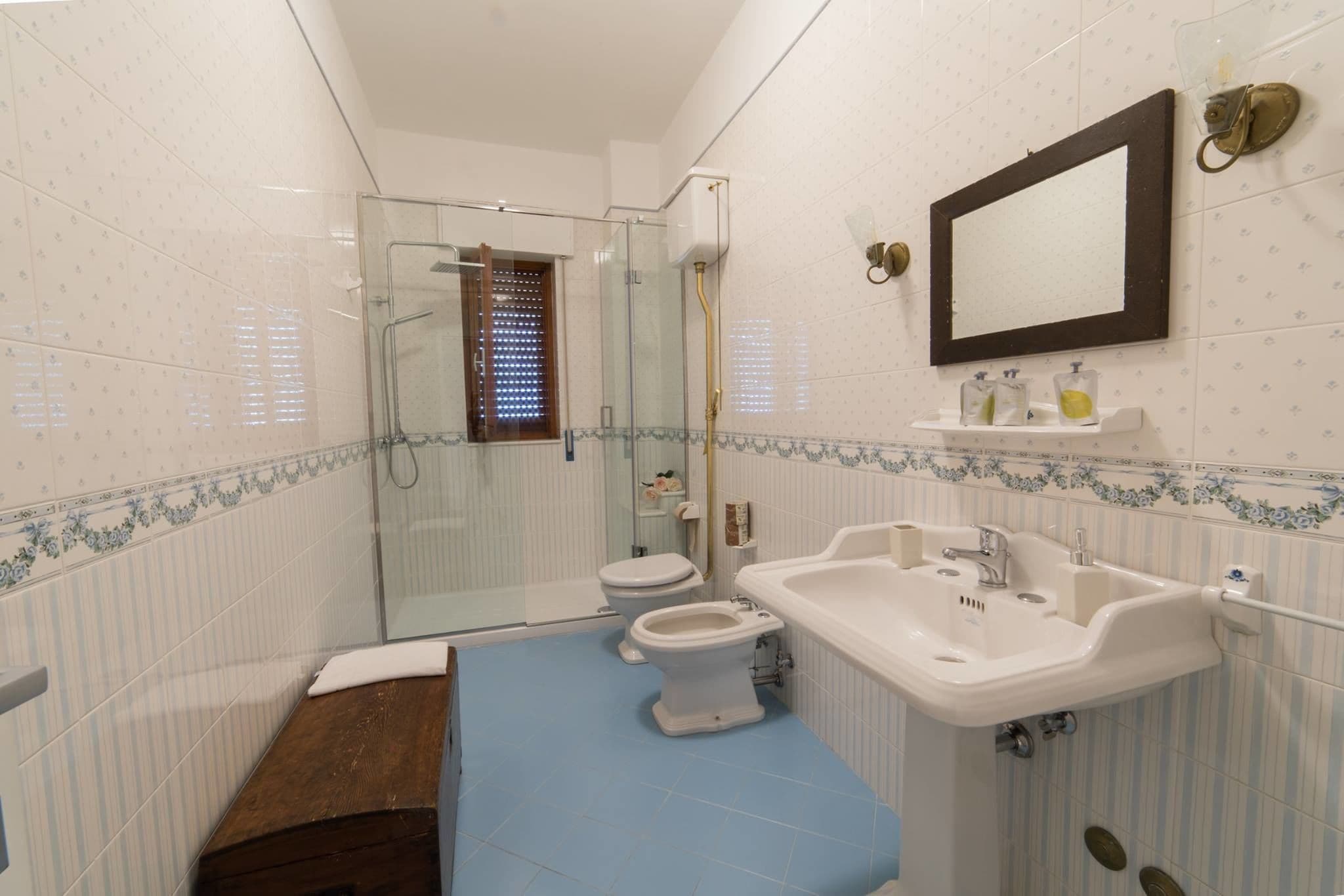 Un baño con cabina de ducha de vidrio, inodoro, lavamanos y espejo.