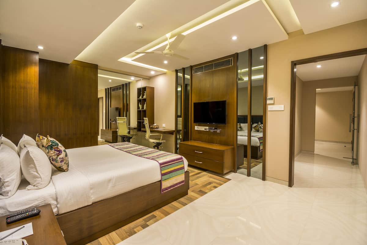 Una habitación de hotel moderna con una cama grande, un escritorio, un armario y un televisor.