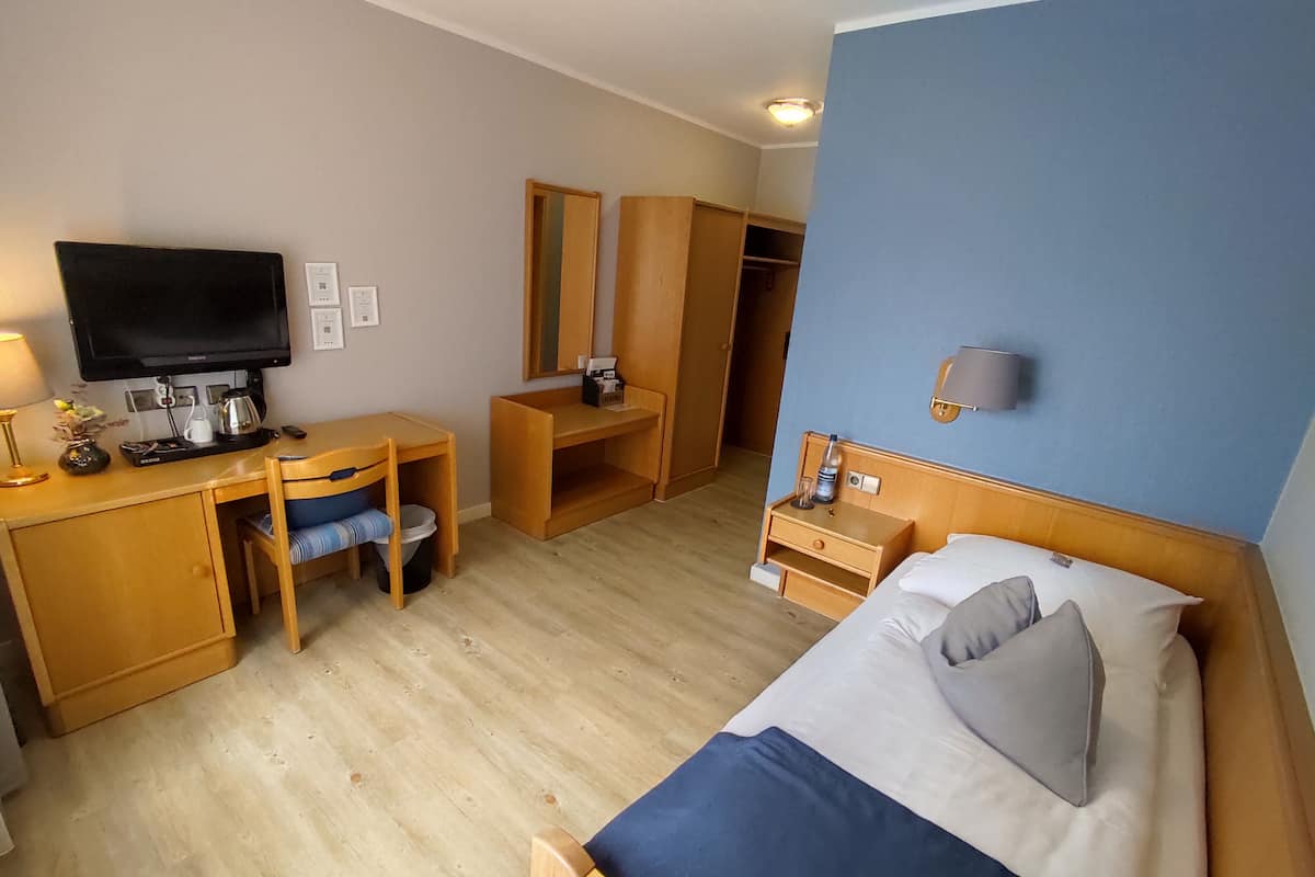Une chambre d’hôtel équipée d’un lit, d’un bureau, d’une chaise, d’une armoire et d’un téléviseur.