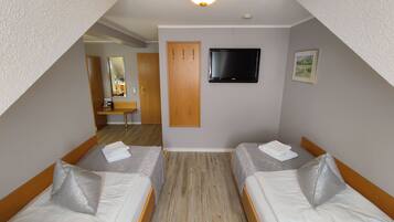 A room with two beds, a TV, and a wooden door.