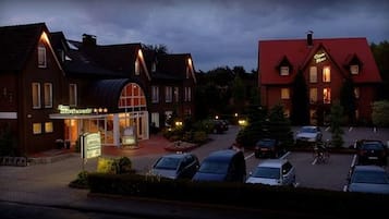 A hotel with a traditional architectural style, featuring a central entrance with a glass facade and a red roof.